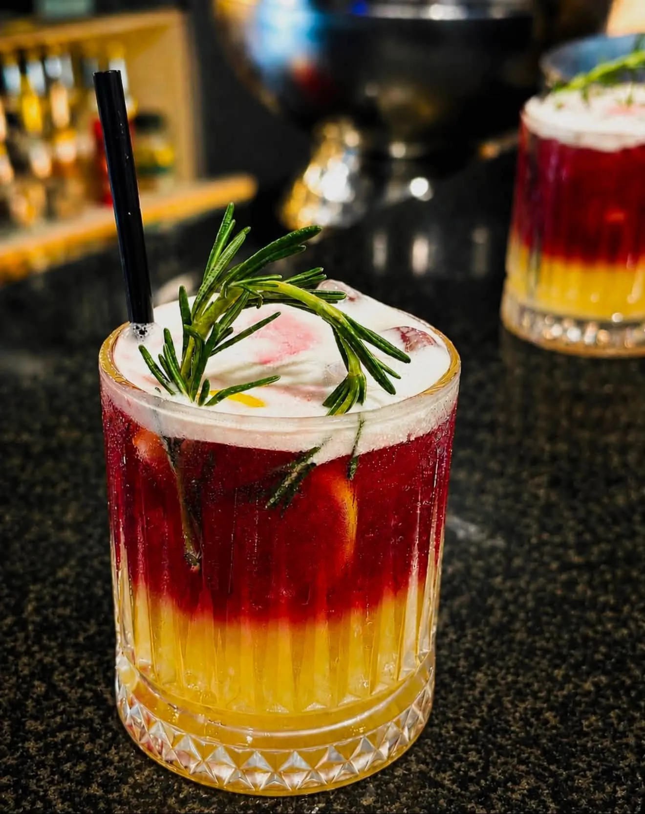 Layered cocktail with rosemary on the bar counter