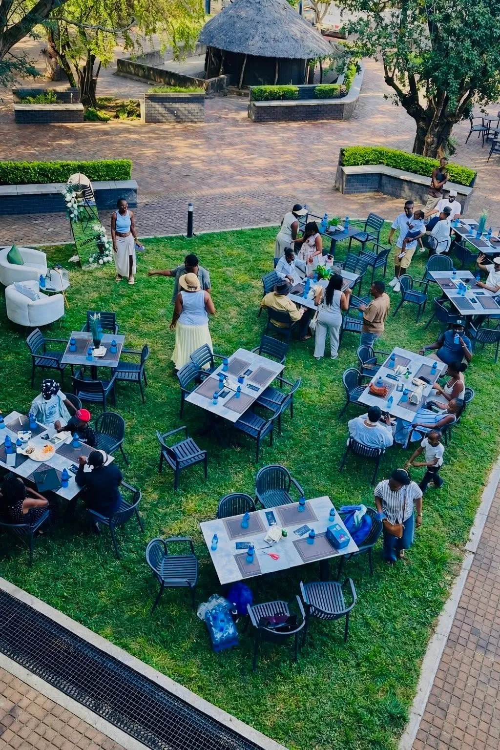 Tables and guests set out across the garden lawn under trees, seen from above