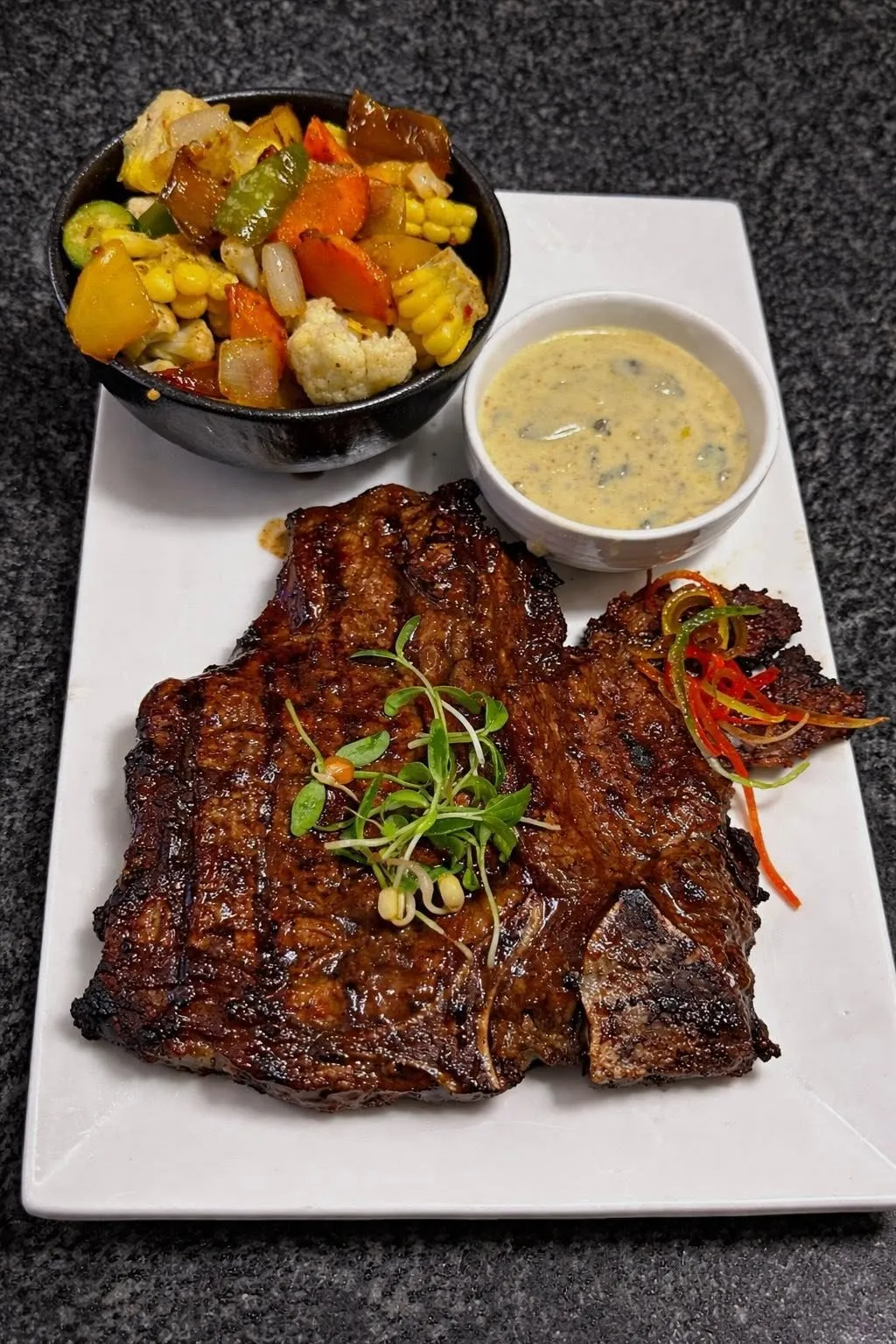 Grilled steak with a bowl of vegetables and sauce