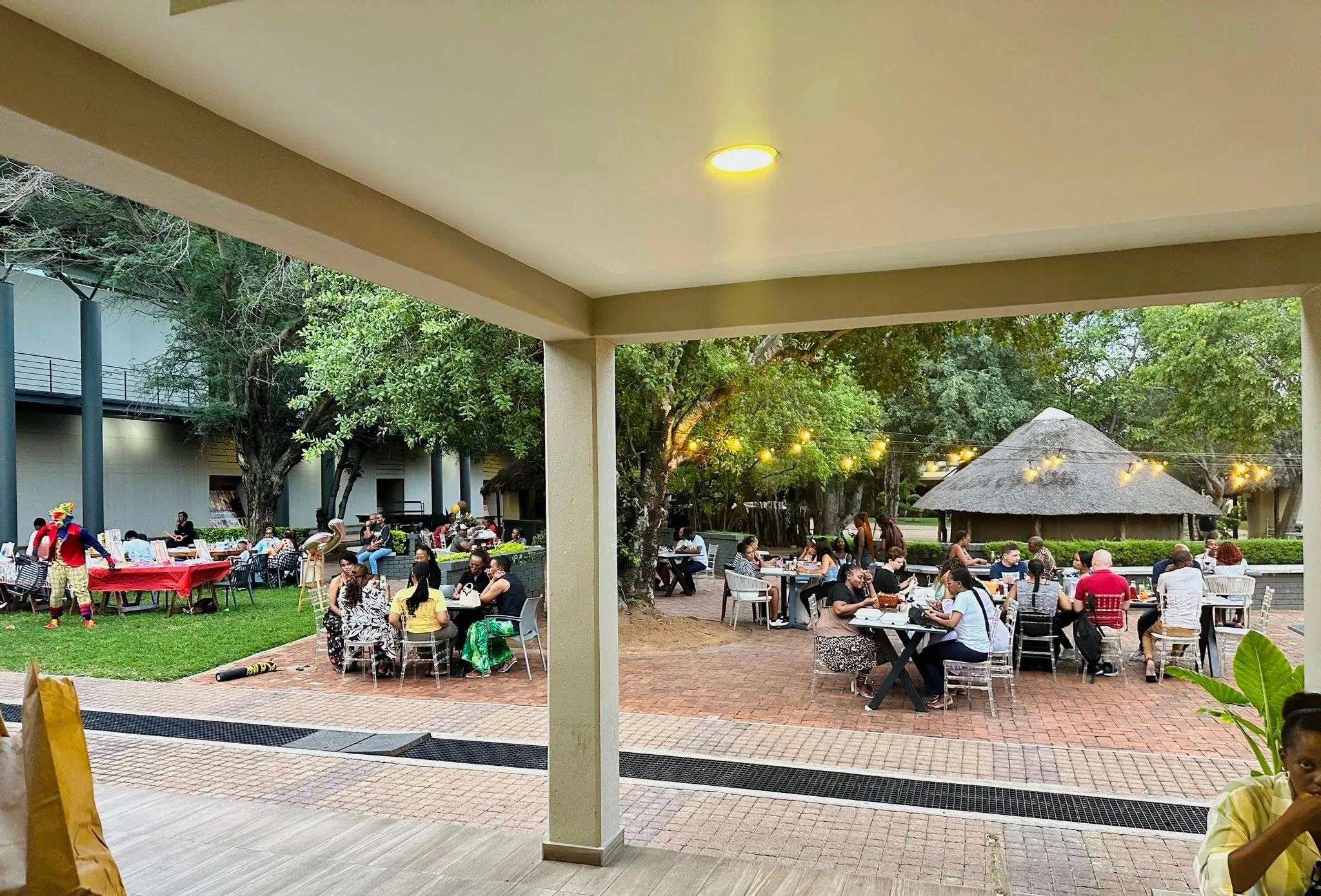 The covered terrace looking out across the lawn, with guests seated at tables under the trees