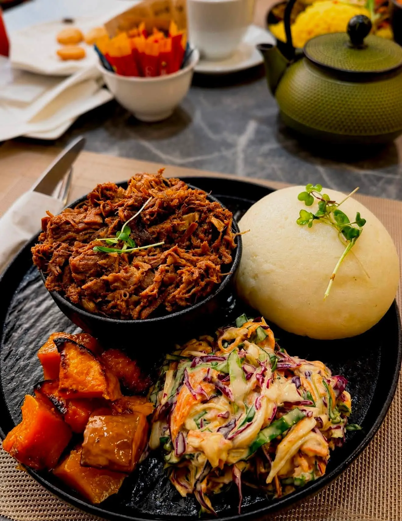 Seswaa with steamed bread, roasted butternut and salad on a dark plate